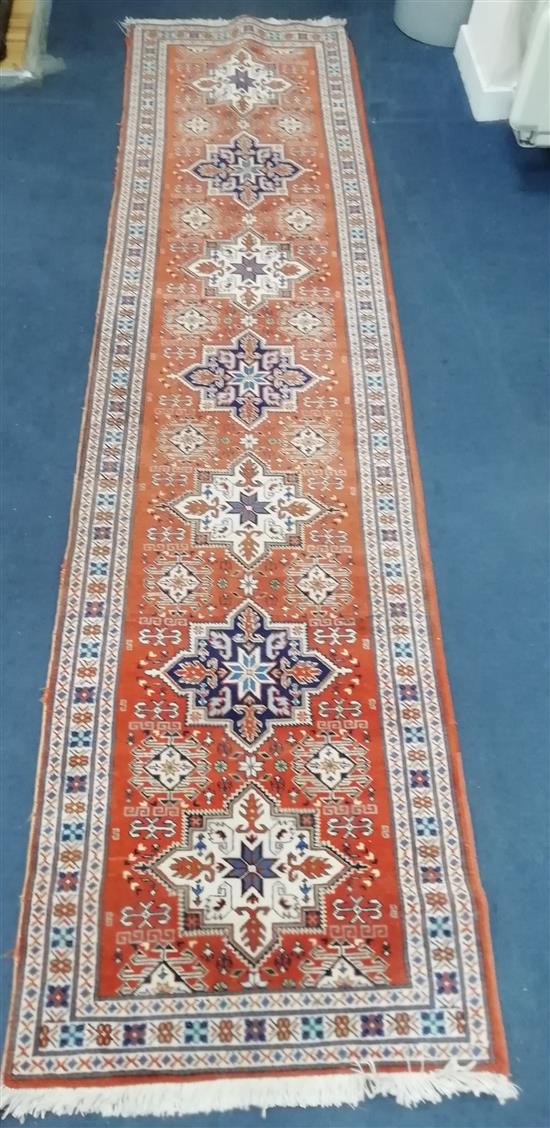 An Eastern rust ground runner, woven with a row of star medallions 300 x 70cm